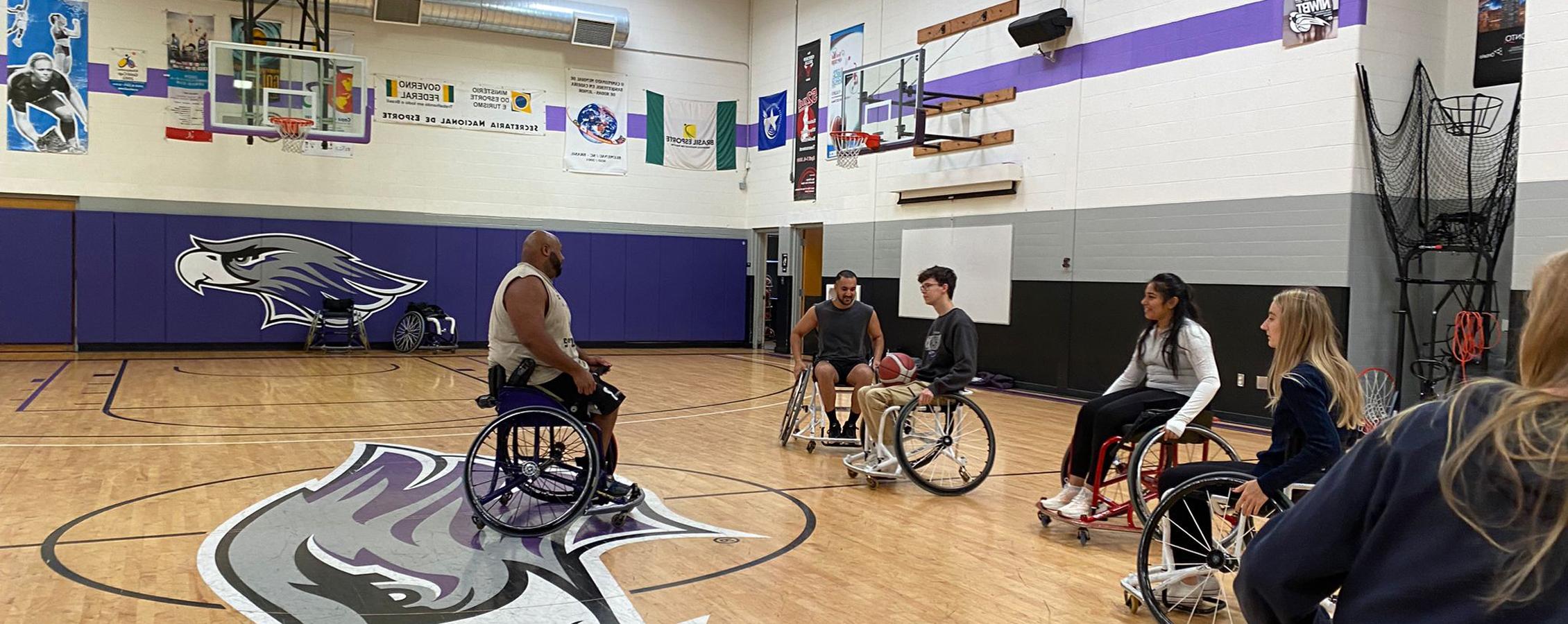 An international student from Sweden coaches wheelchair basketball in a gym.